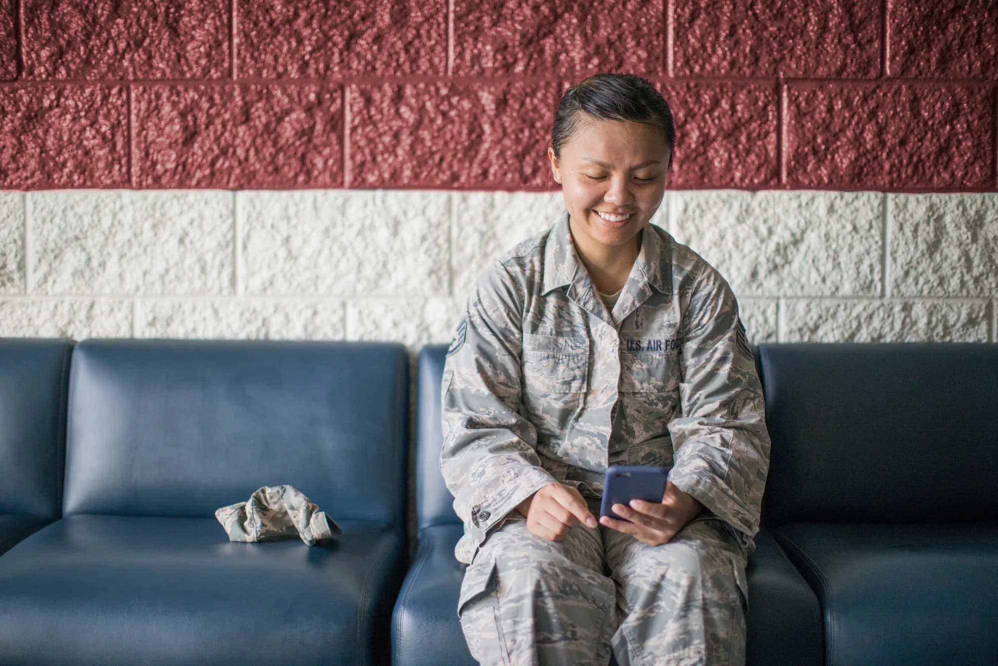 An Air Force servicewoman smiling at a video on her phone